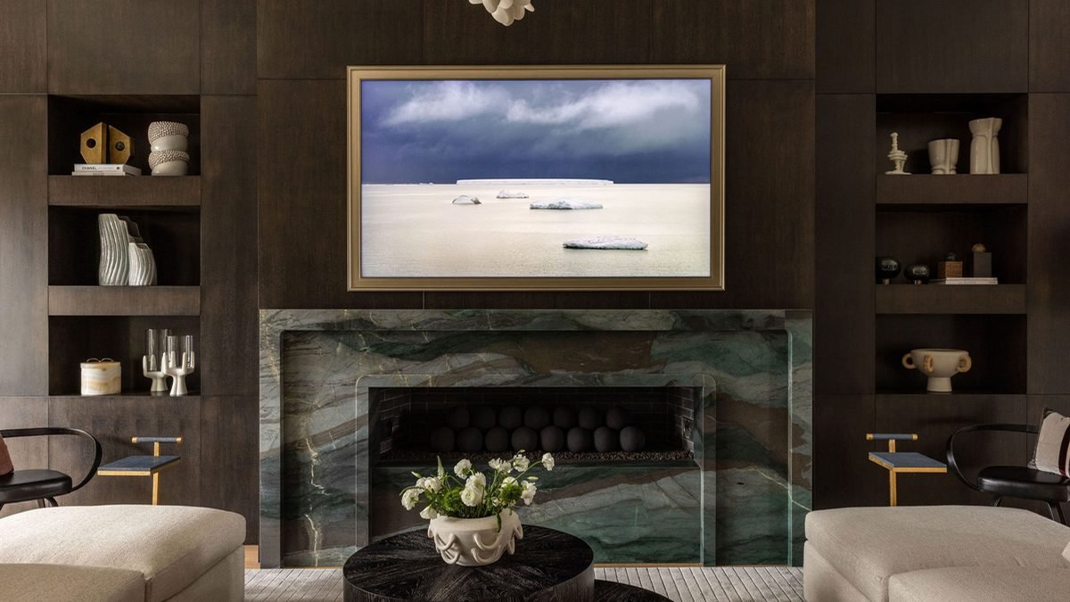 A living room with a green marble fireplace between built in shelving, with seating either side